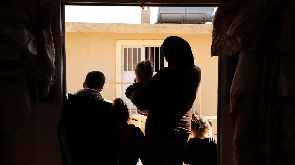 Une femme et ses enfants se tiennent à la fenêtre d’un refuge.